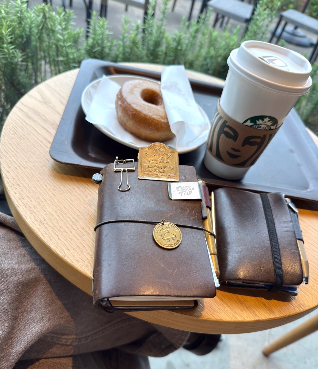 カフェのテーブルに並べたトラベラーズノートとレザーバインダー