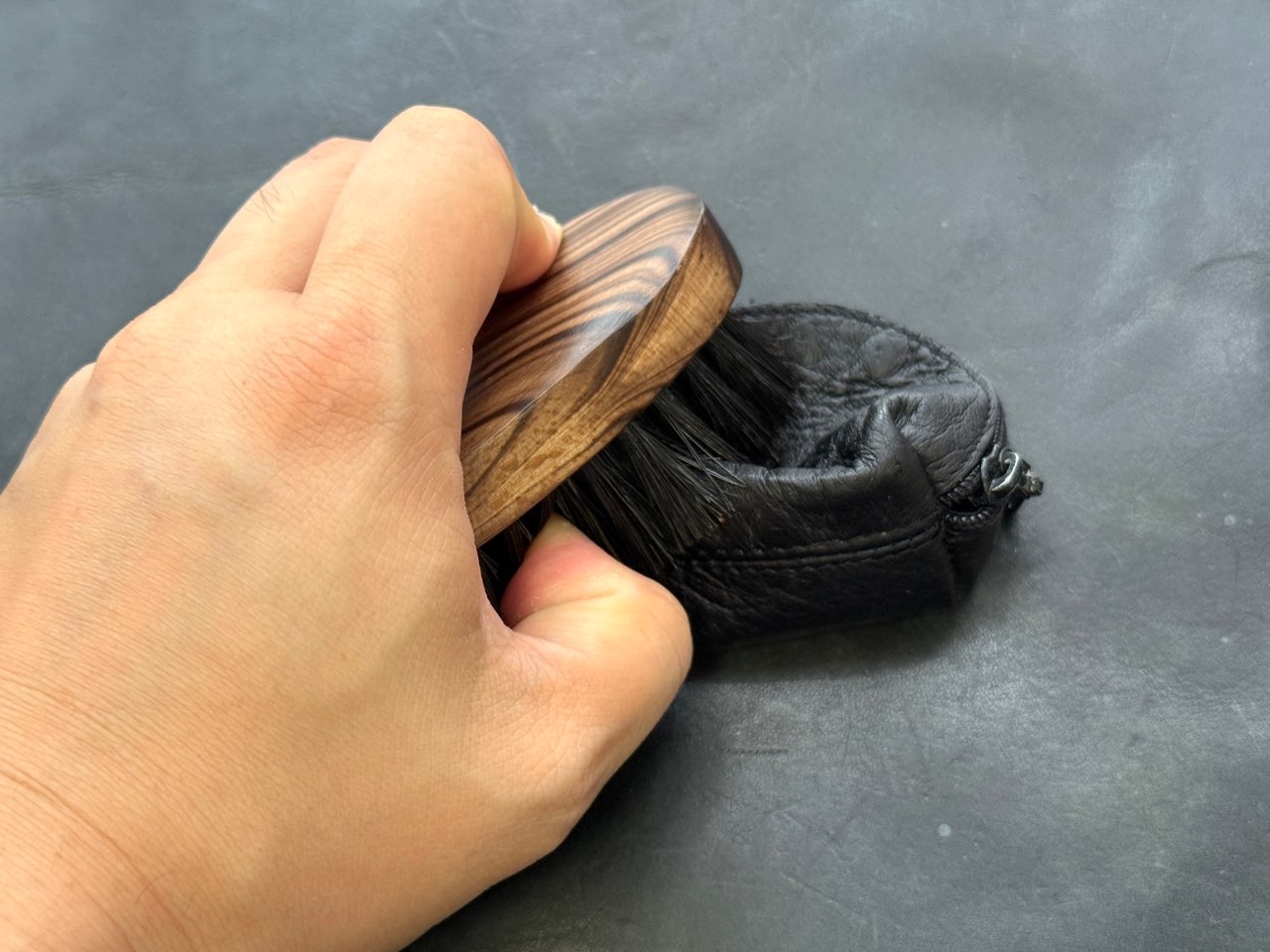 保革クリームをブラシでなじませているオーストリッチレザー