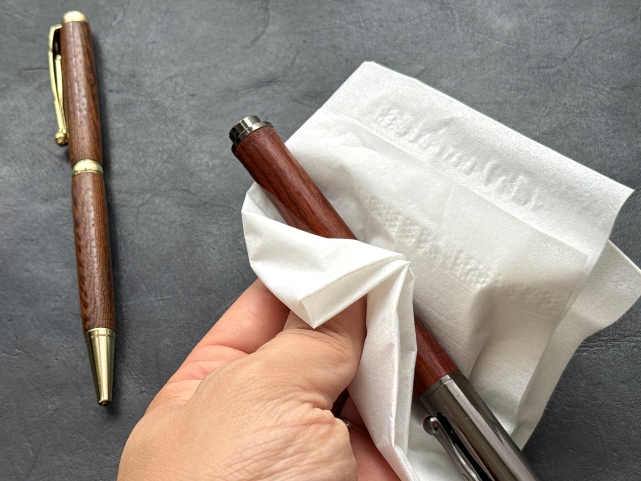 ティッシュで乾拭きしている木軸万年筆
