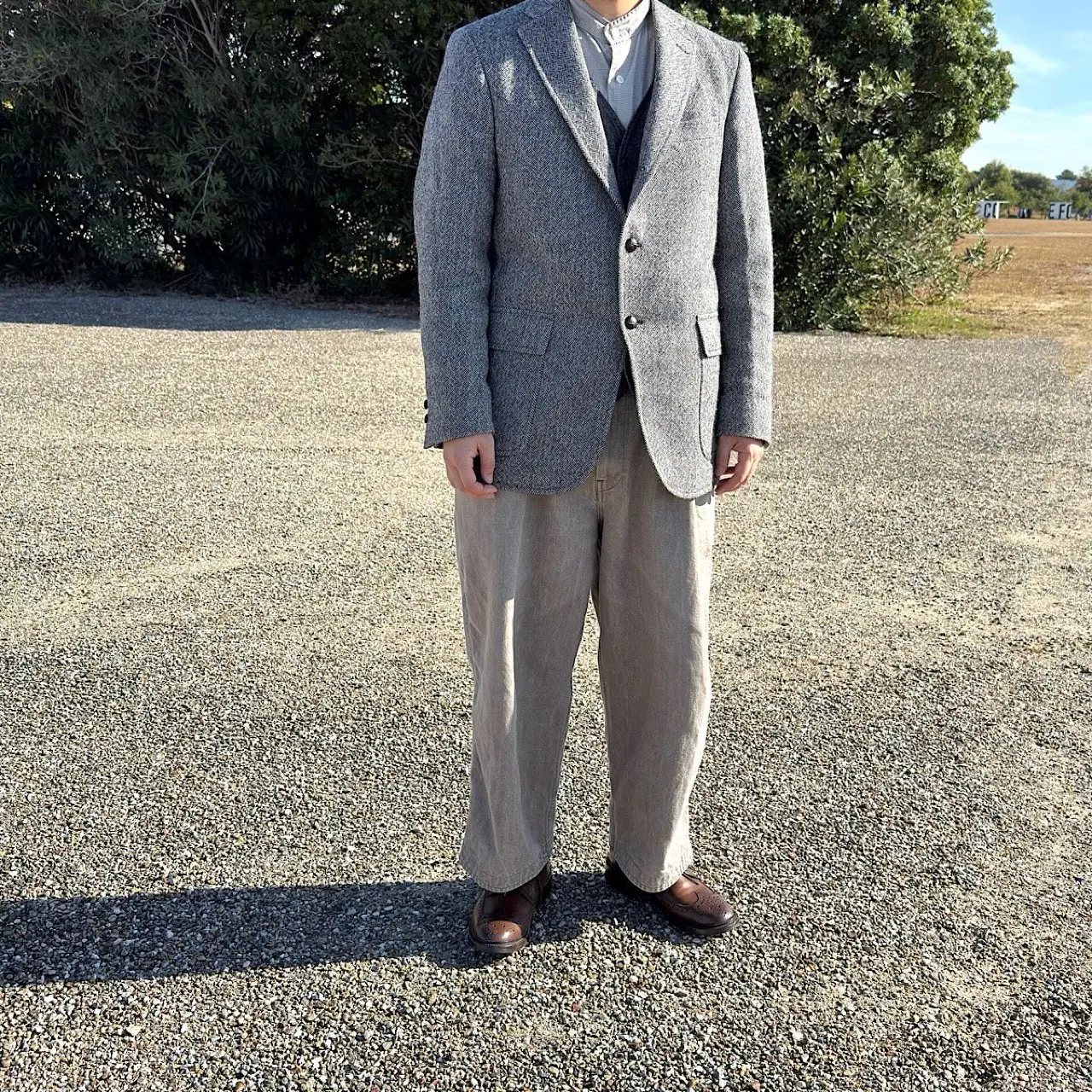 フロントボタンを留めたヘリンボーンツイードジャケット着用図