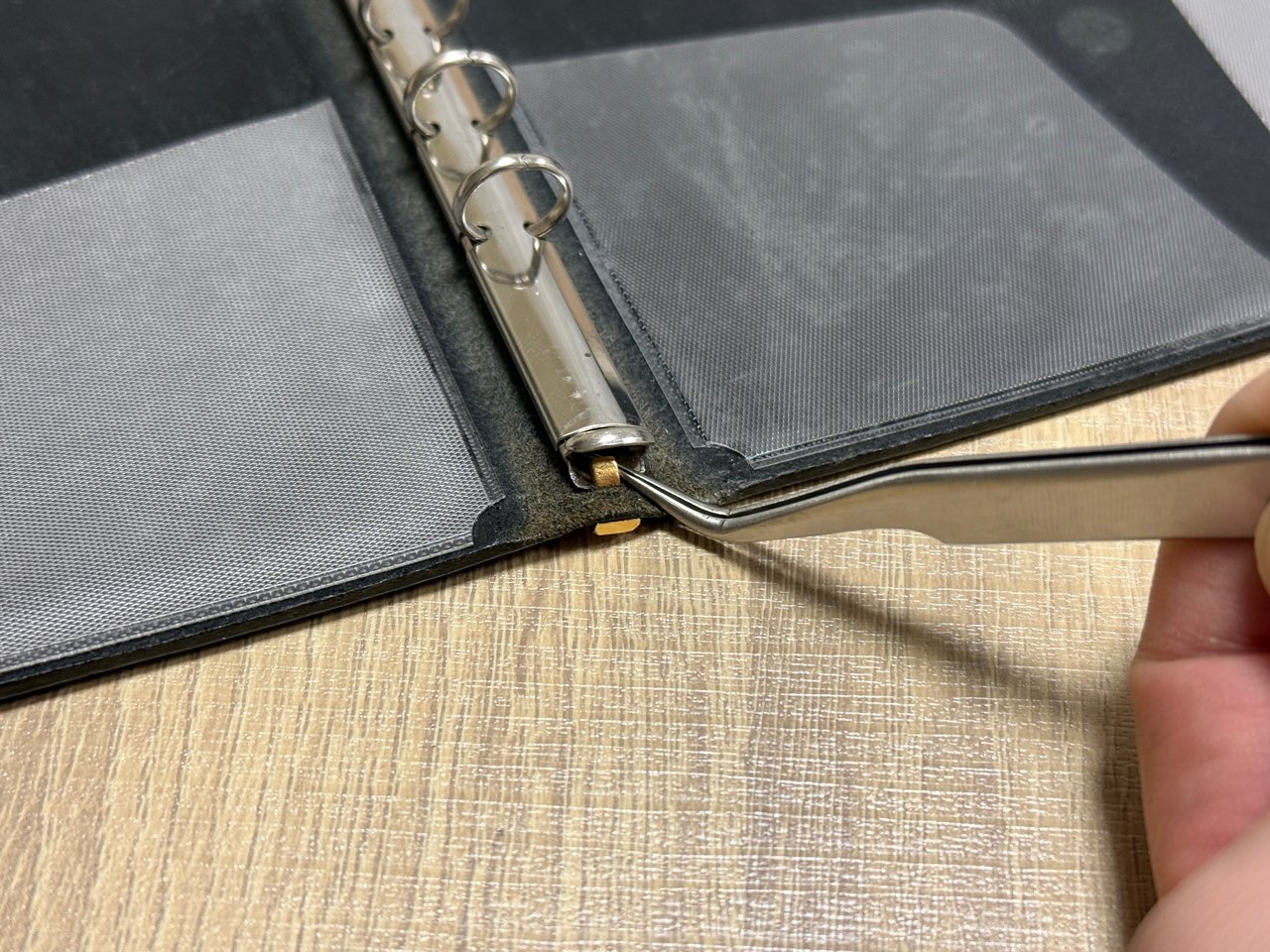 ピンセットでツメを起こしているレザーバインダー